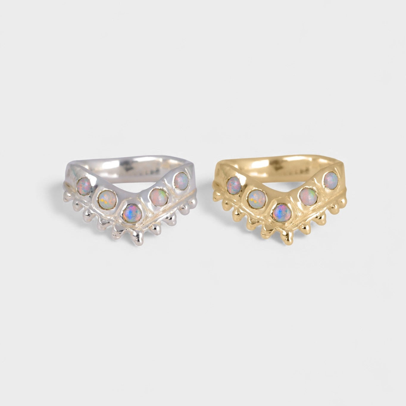 Two rings, one silver and one gold, with gemstone accents on a light gray background.
