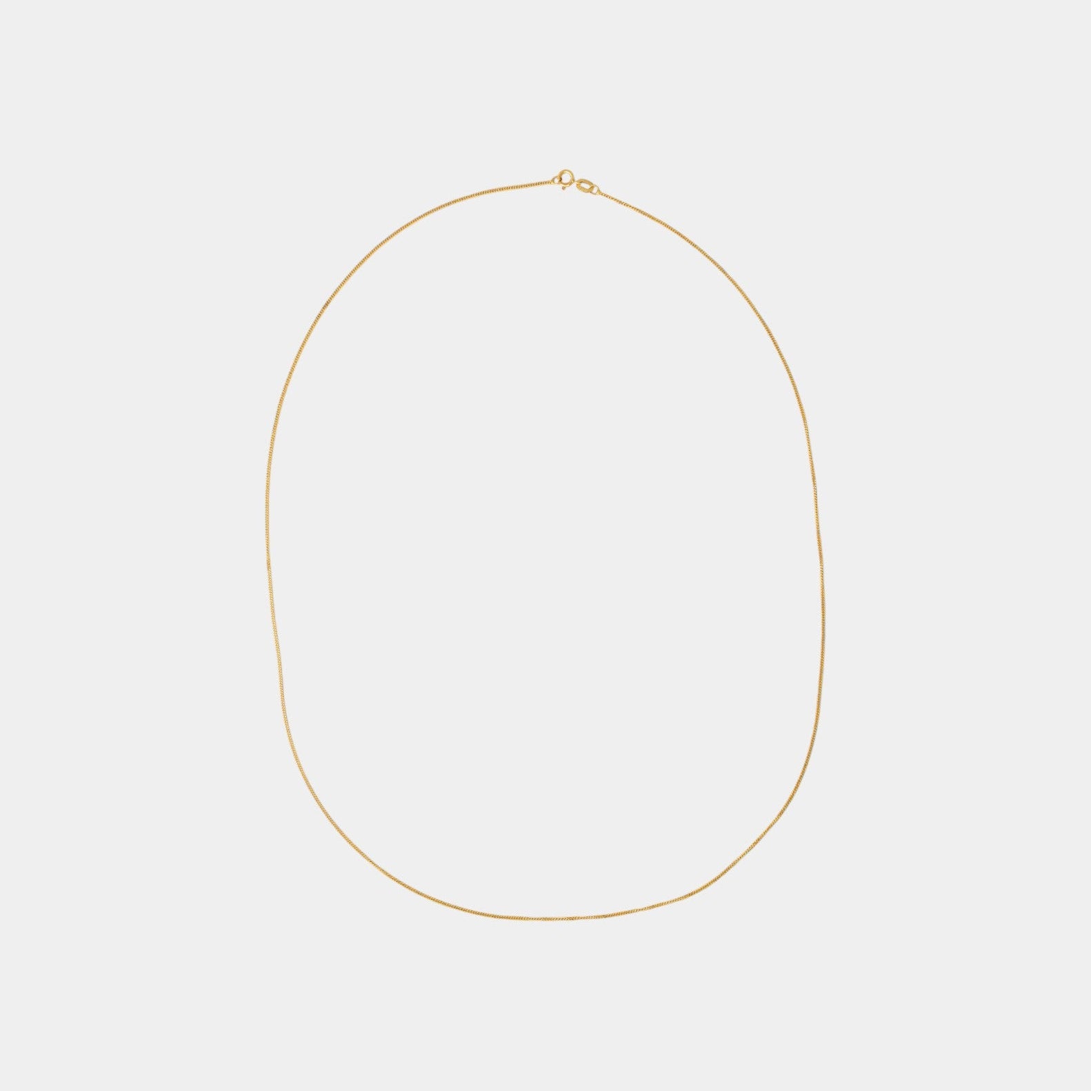 A subtle gold chain necklace laid out on a plain background.