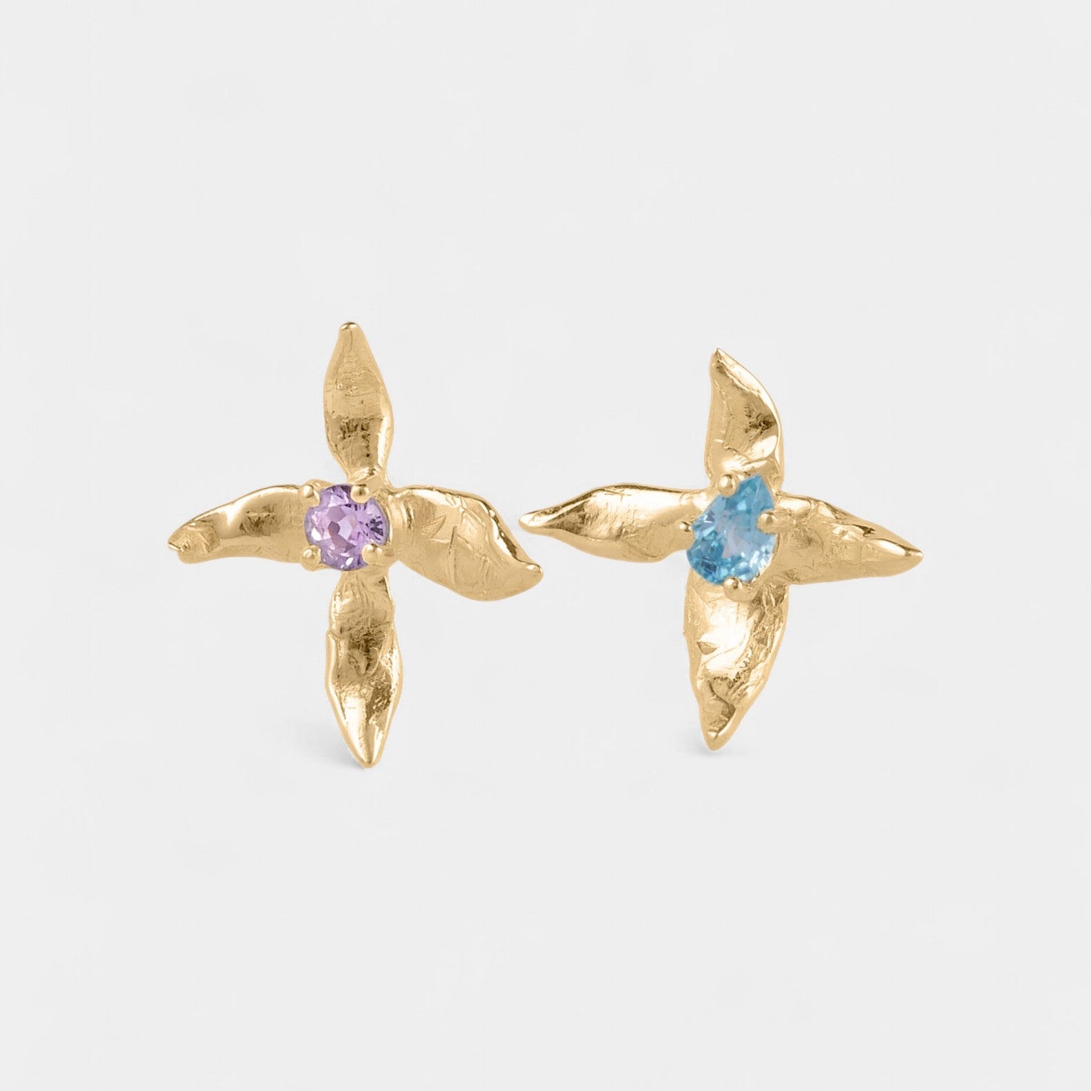 Gold x-shaped earrings with gemstones on a white background