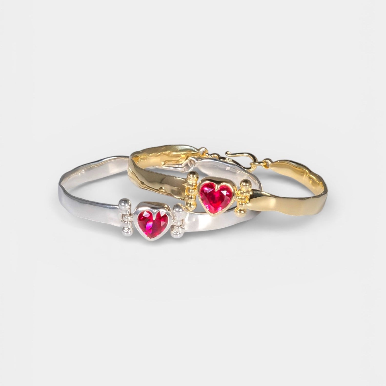 Two heart-shaped bangle designs, one silver and one gold, on a white background.