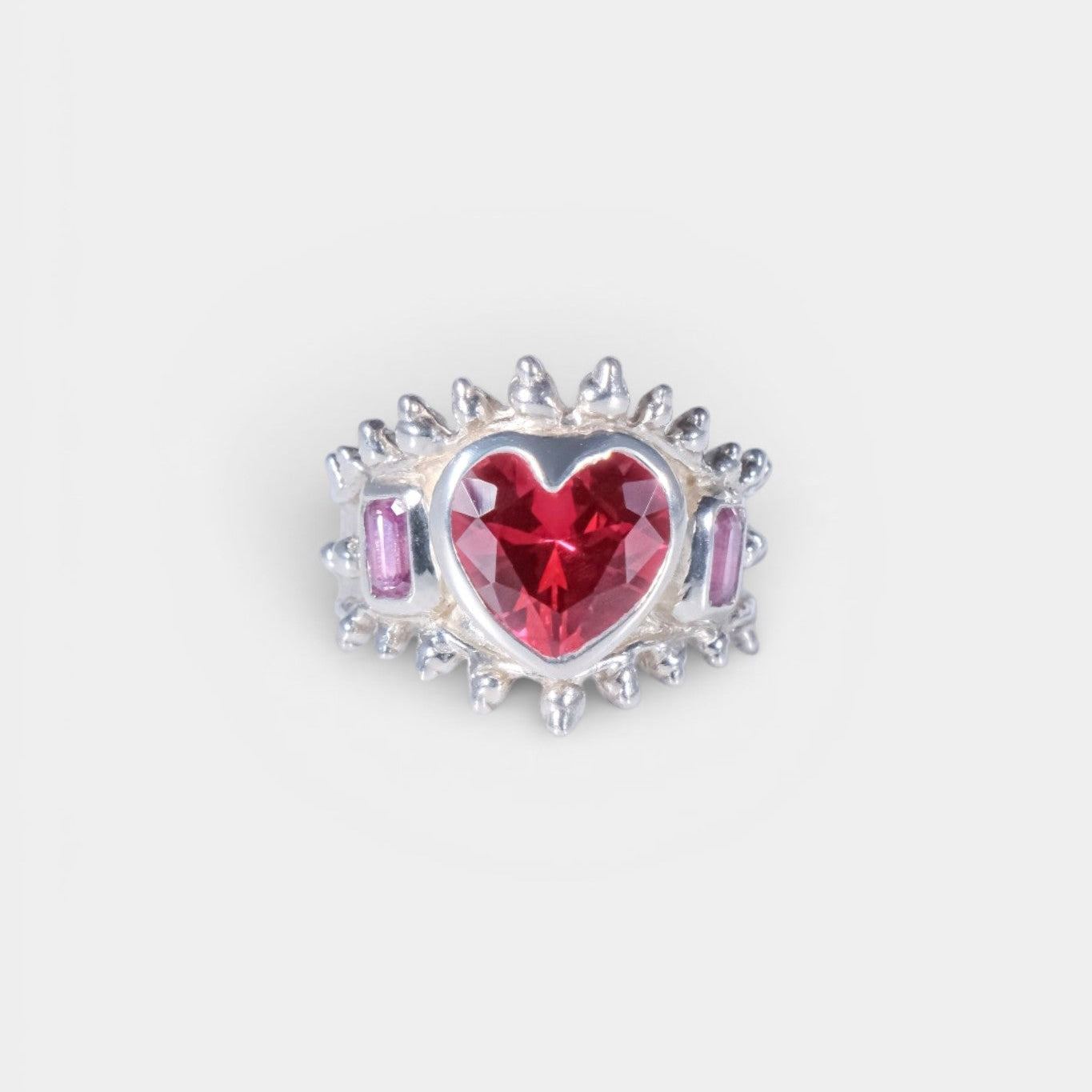 Heart-shaped gemstone with pink and purple accents on a white background