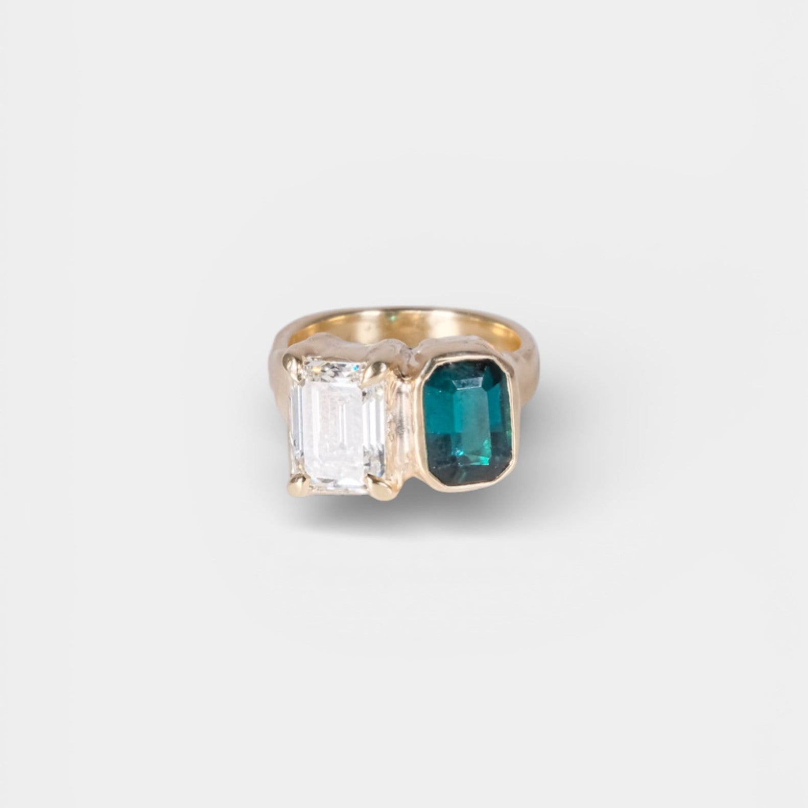 Gold ring with a green gemstone on a white background