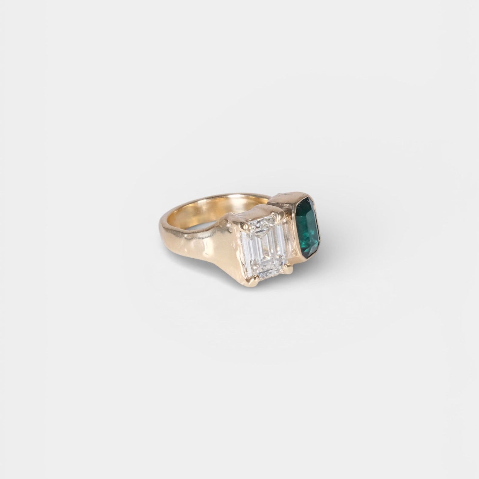 Gold ring with emerald and diamond on a white background