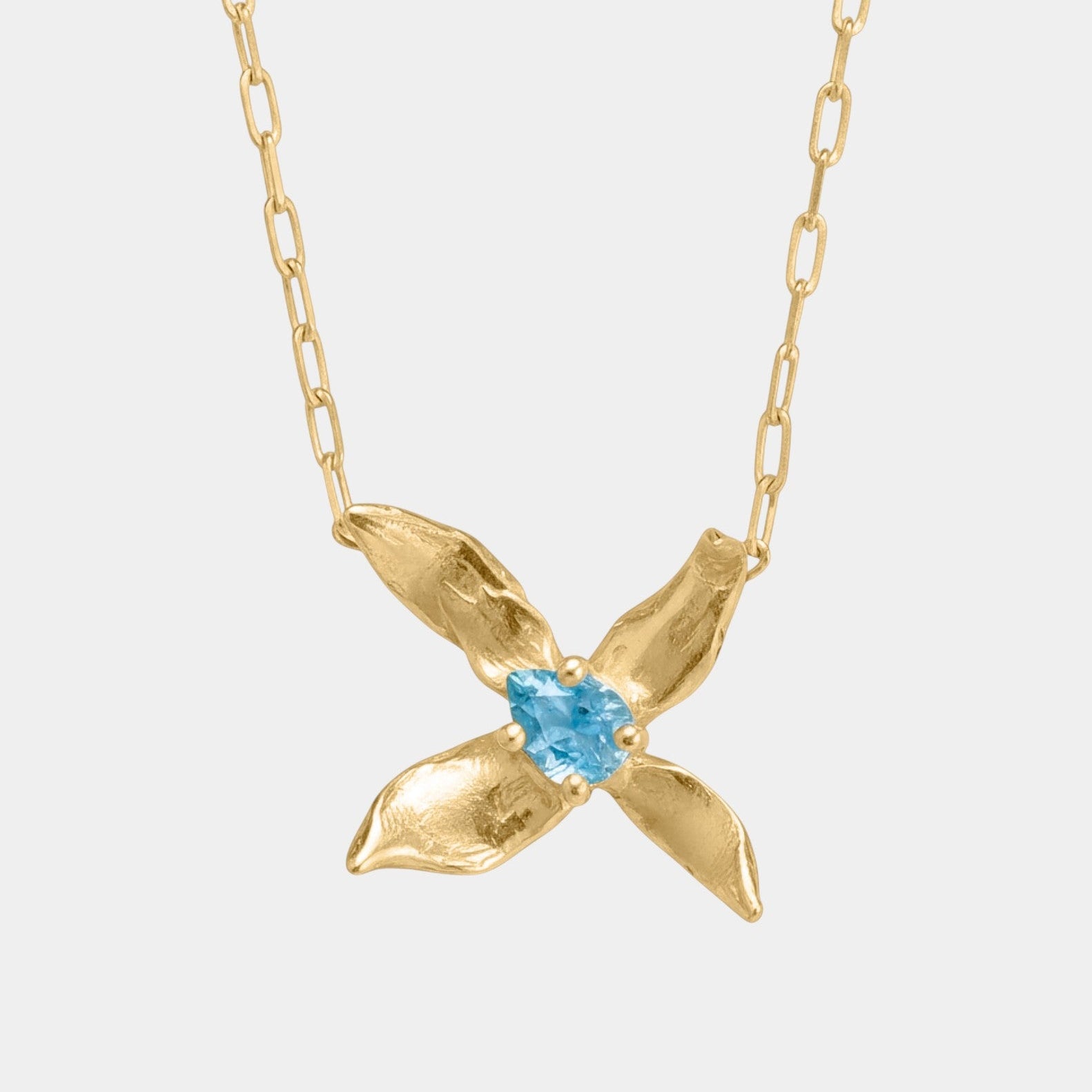 Gold necklace with a blue gemstone pendant on a white background