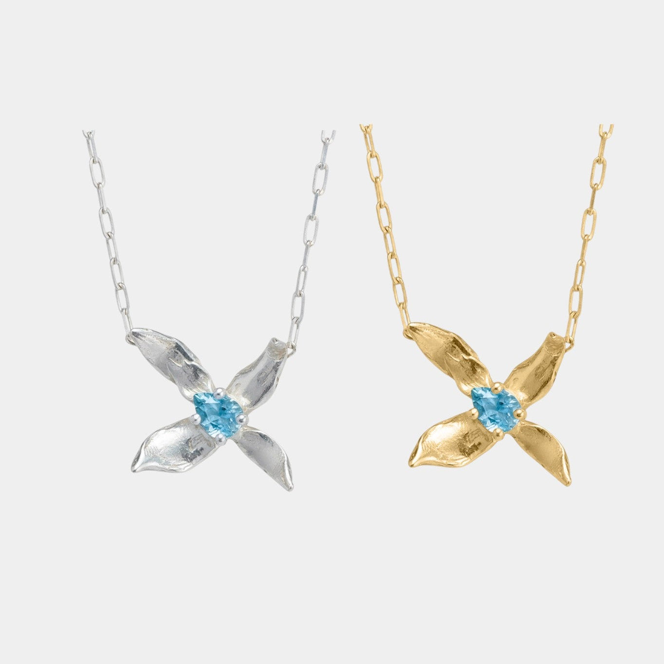 Two necklaces with x-shaped pendants and blue stones on a white background
