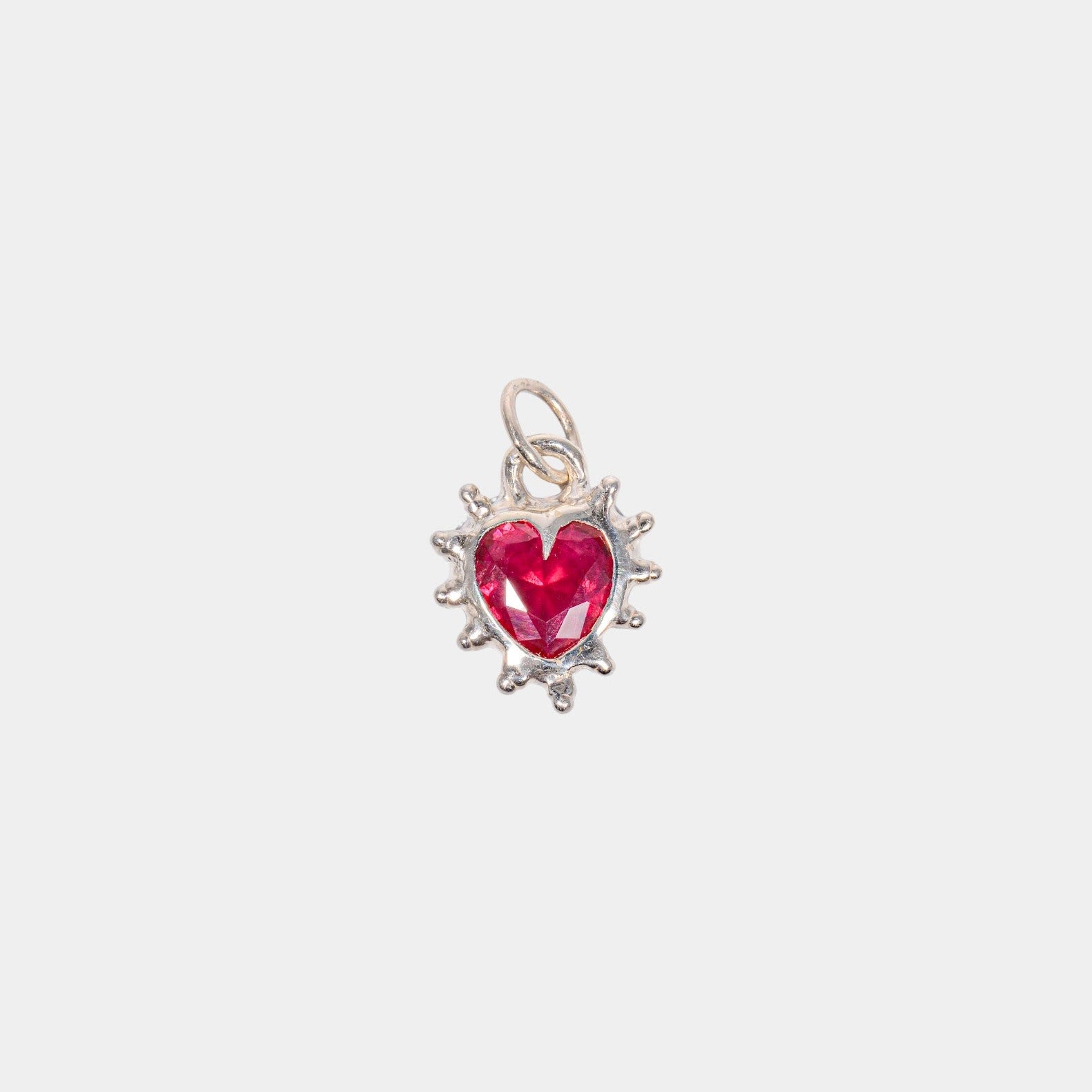 A ruby red heart-shaped pendant with a silver metal setting.