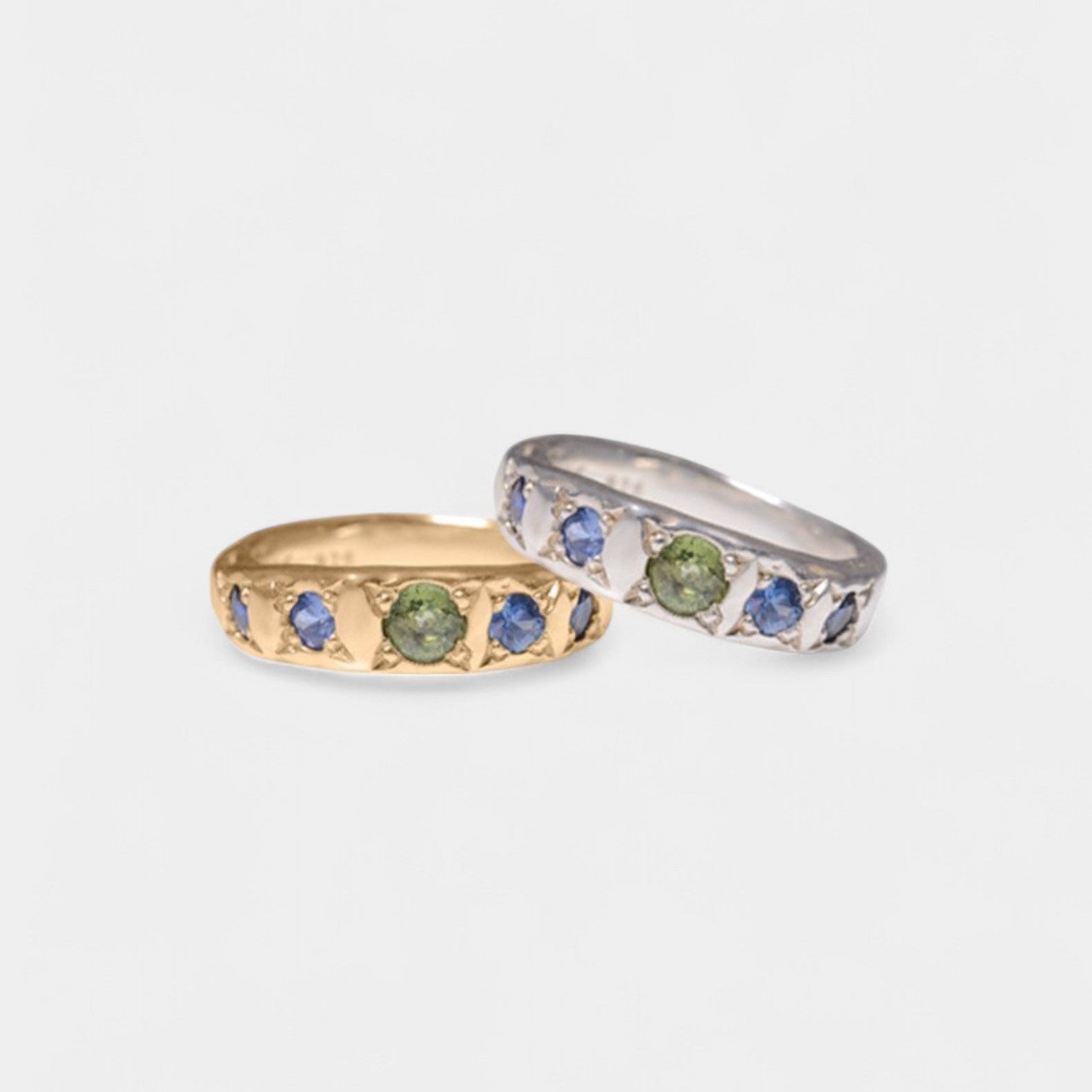 Two rings, one with blue to green fading sapphires set in yellow gold, and the other with a similar color pattern set in silver.