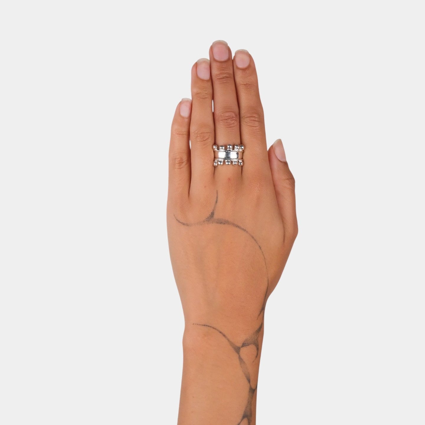 Hand wearing a silver ring on a plain background