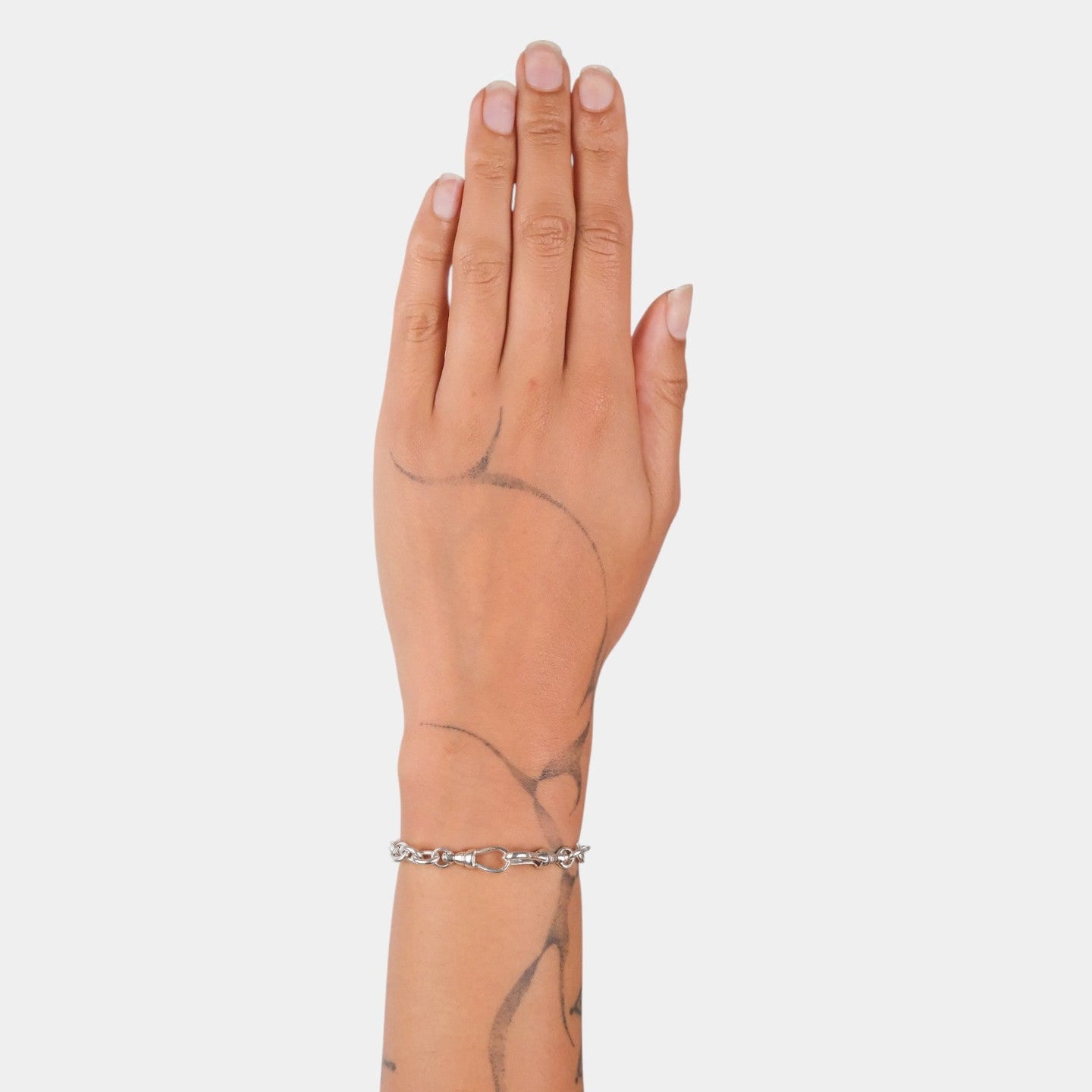 Hand wearing a silver bracelet on a plain background