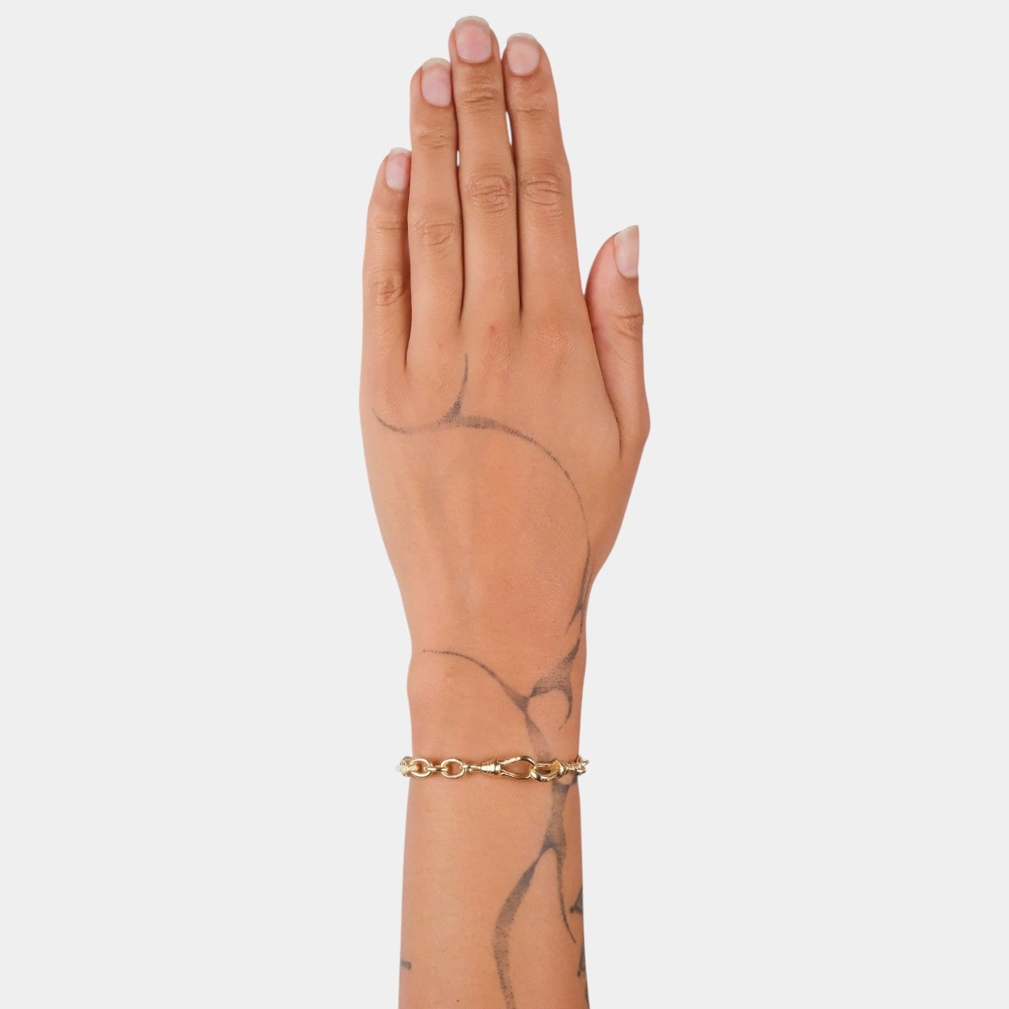 Hand wearing a gold bracelet on a plain background