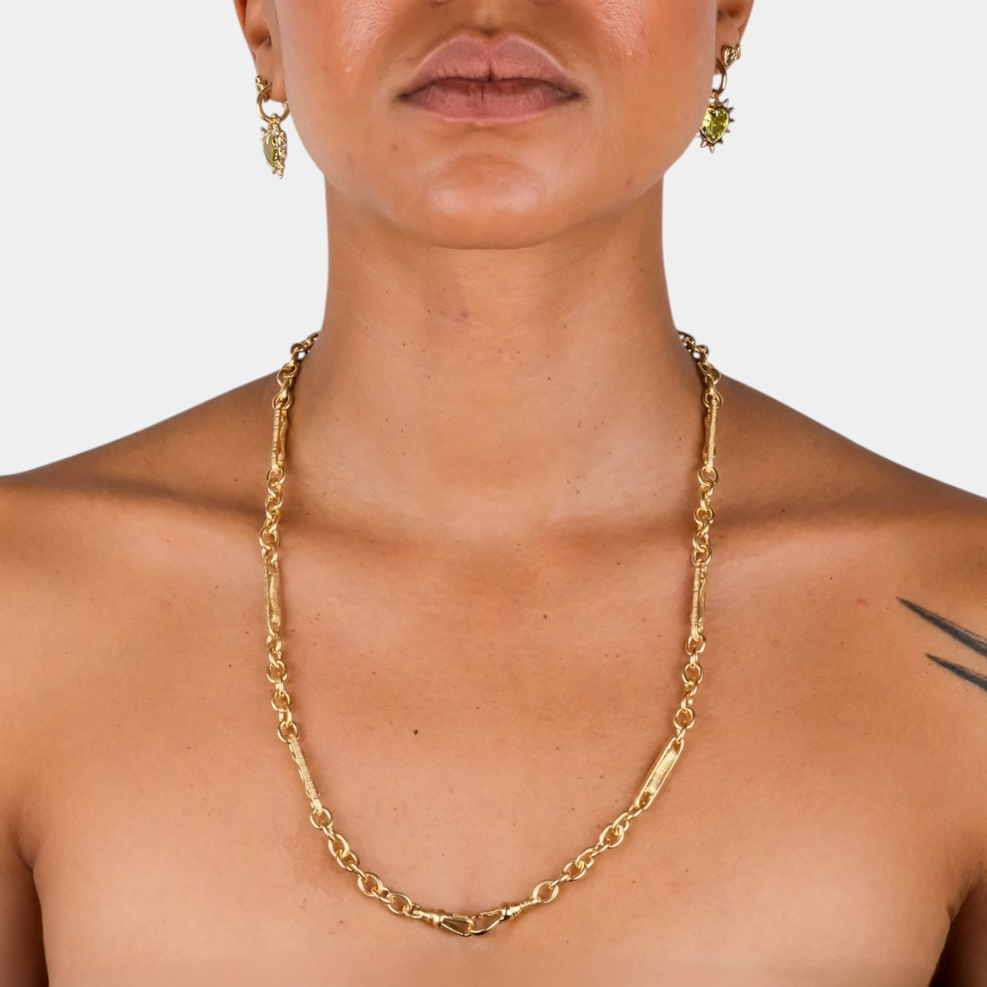 Gold chain necklace worn by a person on a plain background