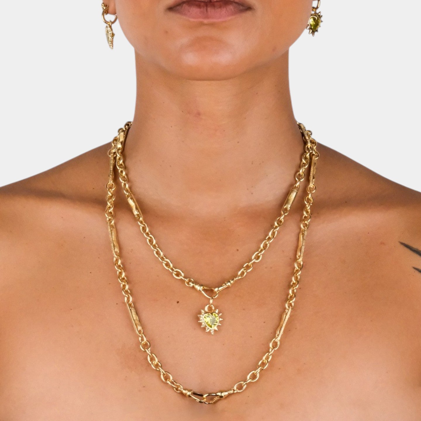 Gold chain necklace with a pendant on a plain background