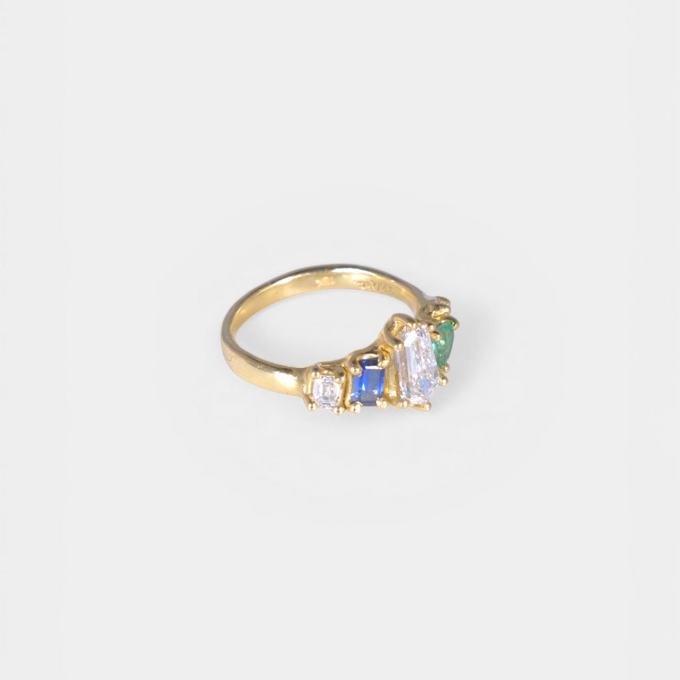 Gold ring with colorful gemstones on a white background