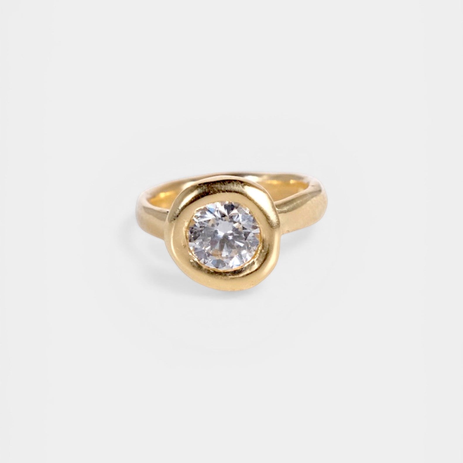 Gold ring with a diamond on a light gray background