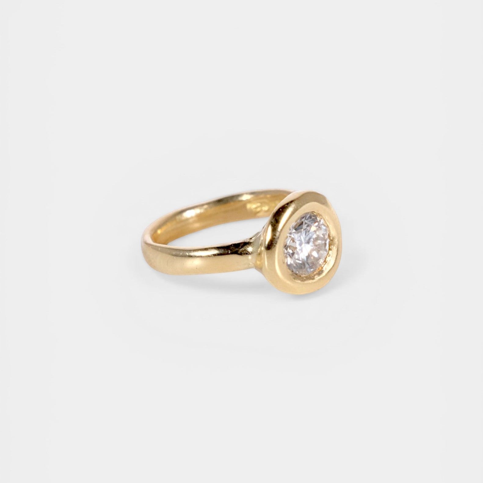 Gold ring with a diamond on a light gray background