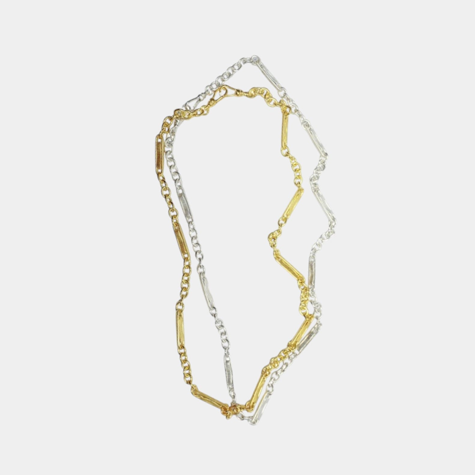A two-tone (silver and gold) long chain necklace laid out on a plain surface.
