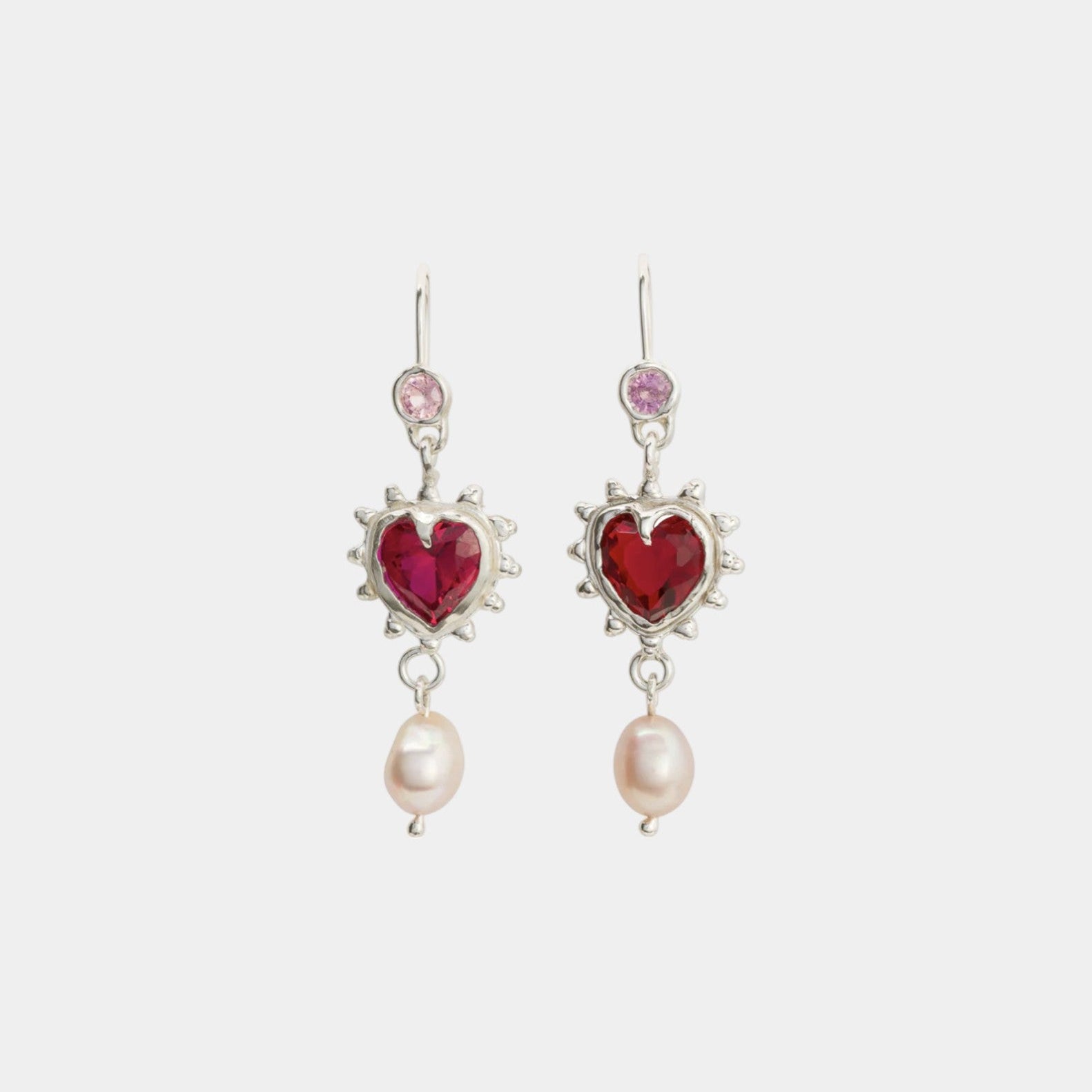 A pair of earrings featuring natural pink sapphire stones with nano ruby hearts and dangling pearls.