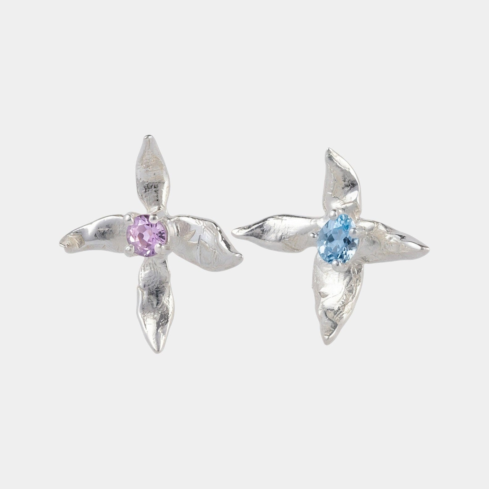 Silver x-shaped earrings with gemstones on a white background