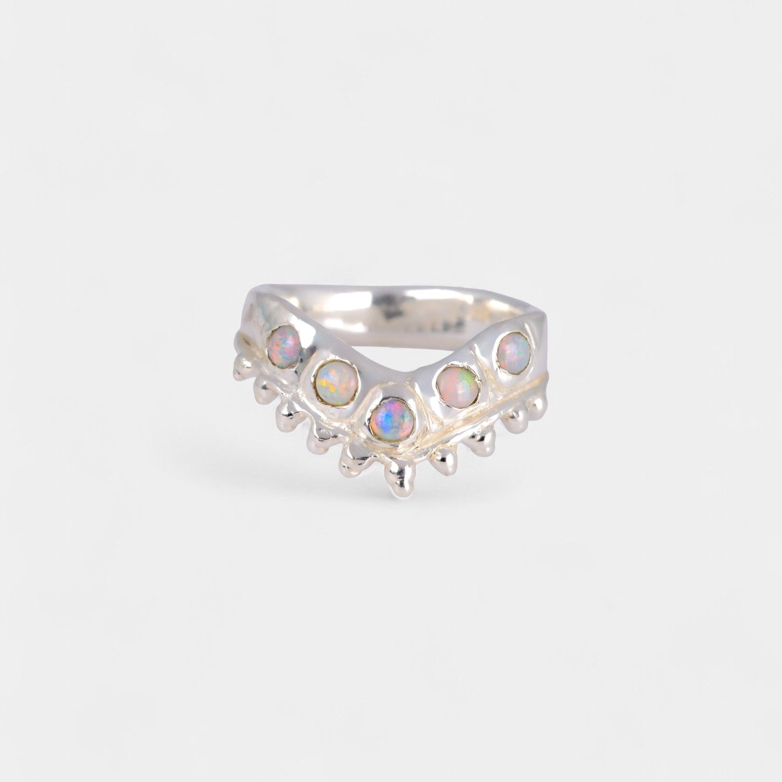 Silver ring with opal stones on a light gray background